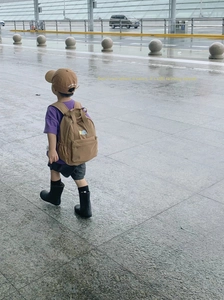 Detail of khaki multi-pocket toddler backpack with embroidery and black rain boots
