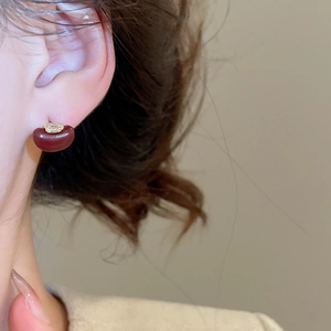 Close-up of a red apple-shaped earring with gold metal and tiny zircon crystals