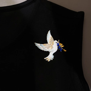 Detailed view of crystal-encrusted dove brooch with olive branch on black fabric