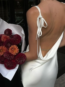 Robe longue blanche en satin dos nu avec col bénitier et chaînes dorées élégantes