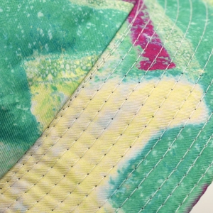 Detailopname van kleurrijke tie-dye stof met nauwkeurig stiksel op een zonnevissershoedje