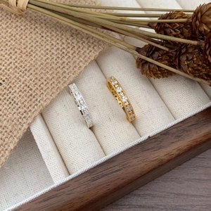 Detailed view of silver and gold zircon rings displayed on a white velvet box liner