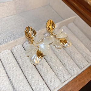 Macro detail of pearlescent acrylic flower earrings with golden metallic accents