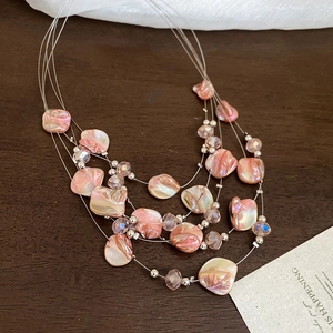 Macro detail of layered beaded necklace with pink shells and clear crystal beads