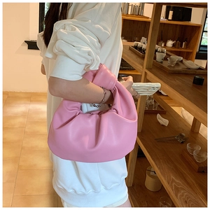 Close-up of pink crescent handbag with knotted handle and pleated leather texture