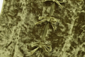 Detailed close-up of velvet olive green fabric texture with elegant bow-tie and cutout design