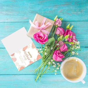 Pink Mother's Day card with gold flowers, gift box and bouquet on blue wood background