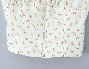Detail of floral chiffon top showing white fabric buttons and red flower print pattern