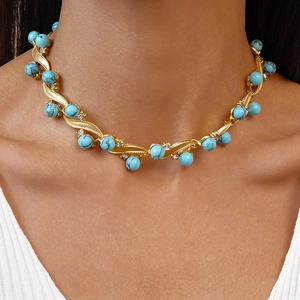 Close-up of gold collar necklace featuring turquoise beads and sparkling crystal accents