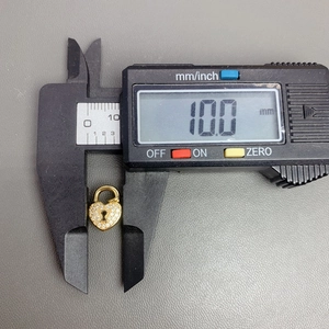 Macro view of crystal paved gold heart lock pendant measuring 10.0mm with digital caliper