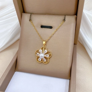 Detail of gold flower pendant necklace with central pearl and teardrop zircon petals