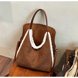 Detailed view of the brown suede tote bag with white faux fur trim on a wooden chair