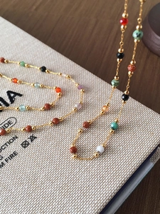 Macro detail of the golden chain necklace with colorful faceted gemstones and sunstone