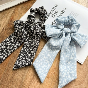 Close-up of black and light blue floral bow scrunchies with white daisy patterns