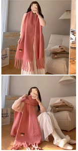 Close-up of soft pink pashmina scarf with long tassels and premium leather brand tag