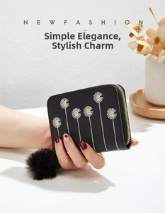 Detail of black faux leather mini wallet with embroidered daisies and pompom keychain