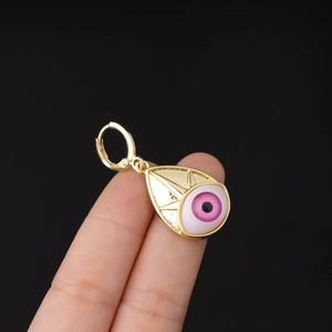 Macro detail of a golden evil eye drop earring featuring a vibrant pink iris design