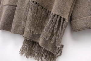 Close-up of tan knit cardigan showing fringe hem detail and high-quality wool texture