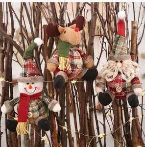 Plaid plush Christmas ornaments with snowman and reindeer hanging on lit branches