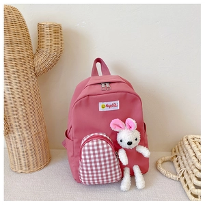 Pink children backpack with red plaid pocket and a cute plush rabbit doll accessory