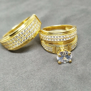 Close-up of gold plated wedding ring set with round centerpiece and micro-pave crystals
