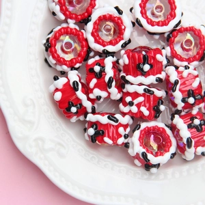 Macro shot of red, white, and black striped glass beads on a white relief ceramic plate
