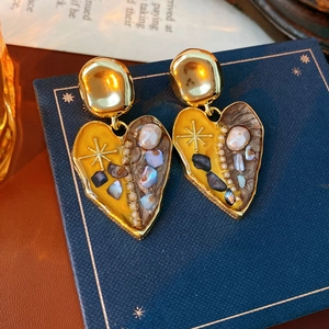 Macro view of vintage heart earrings with pearl inlay and colorful enamel details