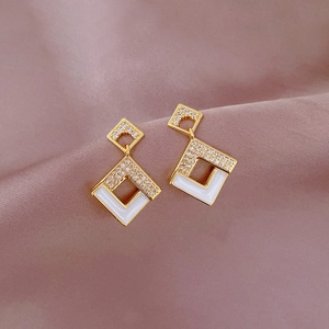 Detail of square gold earrings with white enamel and micro-pave zircons on silk