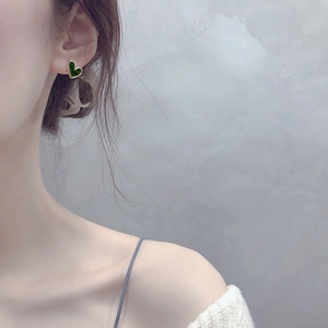 Elegant dark green heart stud earrings with gold trim on model ear stylish accessory