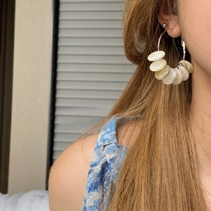Close-up of geometric hoop earrings with marble texture beads on model's ear