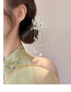 Detail of floral hair stick featuring white lily of the valley and pearl tassels on a model