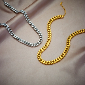 Classic Cuban link chain necklace in gold and silver finish on silk background