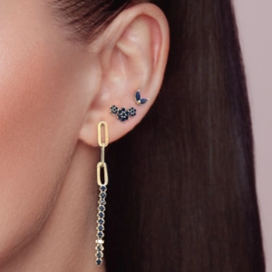 Gold long drop earrings with navy blue gemstones and floral studs on model