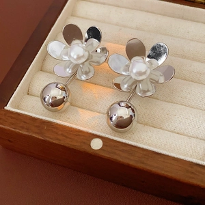 Vue détaillée de boucles d'oreilles fleur argentée et perle avec boule en métal chromé