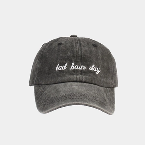 Detail of washed charcoal cotton baseball cap featuring Bad Hair Day white embroidery