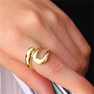 Close-up of a polished golden teardrop open ring with a hollow curve design