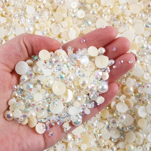 Macro shot of mixed white flatback pearls and sparkling AB crystal rhinestones in hand