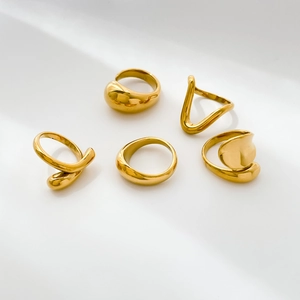 Macro view of five-piece polished gold ring set with minimalist curved and organic shapes