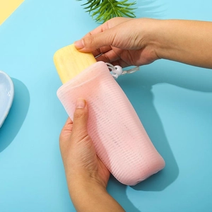 Detail view of 6-layer thickened pink foaming net bag with yellow soap and white drawstring