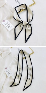 Detail of a chic cream skinny scarf with black edges and Love Never Fails Paris print