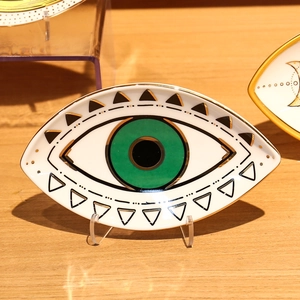 Detail van keramische sieradenschaal met groen oog, gouden rand en geometrisch dessin