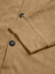 Macro view of camel corduroy fabric texture and matte black buttons on shirt cuffs