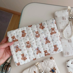 Detailed macro view of quilted cotton fabric bag featuring cute brown bear and floral patterns