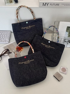 Embroidered denim mini tote bag with colorful woven handles and snap closure
