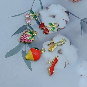 Macro detail of mixed fruit charms including cherry and strawberry with colorful enamel