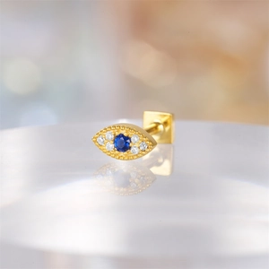Macro shot of gold Evil Eye cartilage stud earring with blue stone and clear zircons
