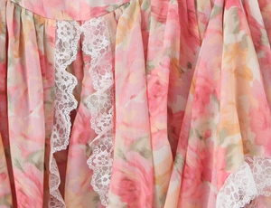 Detailansicht aus nächster Nähe von rosa floralem Chiffon mit weißem Spitzenbesatz