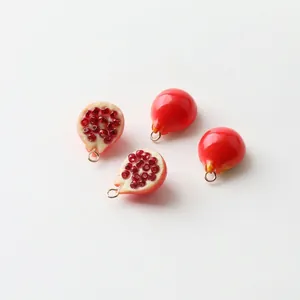 Detailed macro view of four resin pomegranate charms with gold loops for DIY jewelry