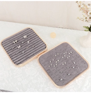 Close-up of square velvet jewelry display trays with gold metal edges and ring slots