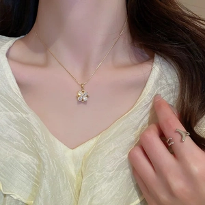 Detailed view of a gold clover necklace and crescent ring on a female model